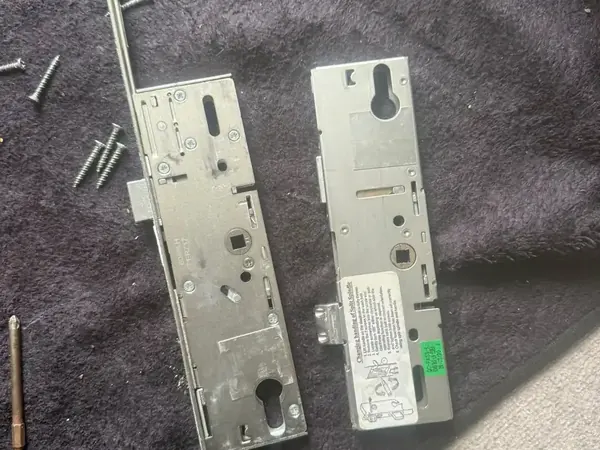 Old and new uPVC multipoint lock mechanisms laid side by side with fixing screws