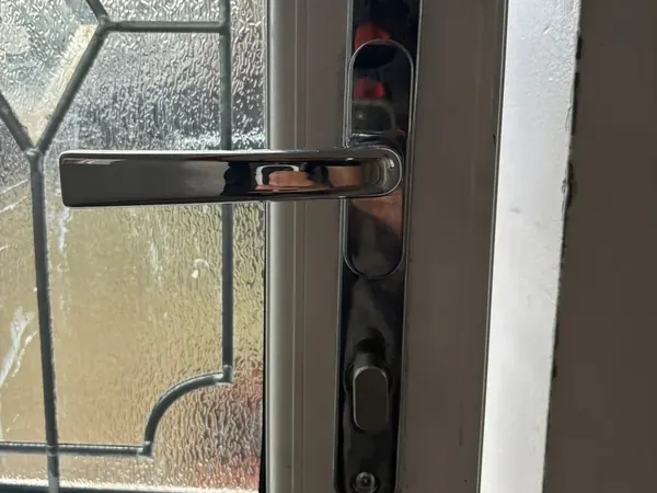 Chrome lever handle on a uPVC door with leaded glass panel